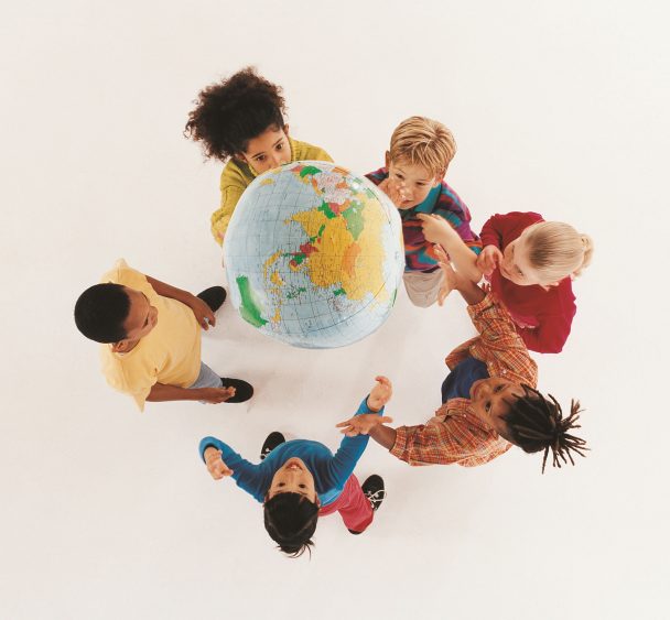 Kinder spielen mit einem Luftball, der wie eine Weltkugel aussieht.